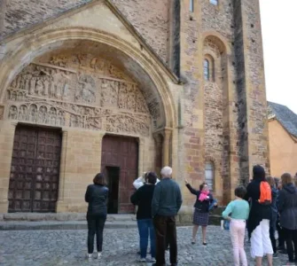 Groupe en visite guidée devant le tympan (Service Patrimoine de Conques)